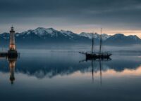 Panorama des Bodensees zur blauen Stunde mit Alpen im Hintergrund und dem Leuchtturm von Lindau