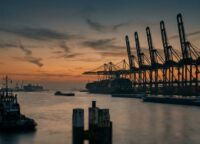 Rotterdam Europoort in der Abenddämmerung mit Containerkränen als Silhouetten vor orangefarbenem Himmel