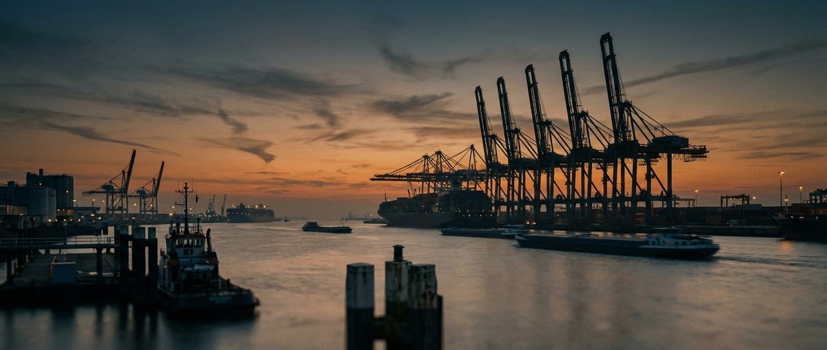 Rotterdam Europoort in der Abenddämmerung mit Containerkränen als Silhouetten vor orangefarbenem Himmel